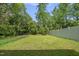 Large, lush backyard featuring a fire pit and bordered by privacy fence and mature trees at 398 Carolina Ave, Raleigh, NC 27606
