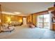 Bright living room featuring wood paneling, comfortable seating, and sliding glass doors leading to the outdoor area at 4005 King Charles Rd, Durham, NC 27707