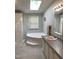Bright bathroom featuring a large soaking tub, skylight, and tiled floor at 4172 Copeland Ter, Graham, NC 27253