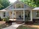 Charming home exterior featuring a covered front porch with seating and landscaped garden beds at 4172 Copeland Ter, Graham, NC 27253