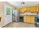 Kitchen featuring stainless steel refrigerator, black appliances, wood cabinets and door to the backyard at 5860 Andover Dr, Graham, NC 27253