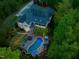 Aerial view of the property featuring a sparkling pool, a cozy fire pit, and landscaped backyard at twilight at 6824 Wood Forest Dr, Cary, NC 27519
