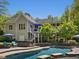 Home exterior with a back deck, pool, hot tub, and patio surrounded by manicured landscaping, creating a private retreat at 6824 Wood Forest Dr, Cary, NC 27519