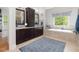Bathroom with dark wood cabinets, double sinks, a soaking tub, and natural light from the window at 6824 Wood Forest Dr, Cary, NC 27519