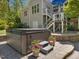 Backyard view of a hot tub with seating and decorative flower pots on a paver patio with an elevated deck and house at 6824 Wood Forest Dr, Cary, NC 27519