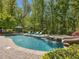 Resort-style pool featuring a waterfall feature, slide, poolside lounge chairs, and lush landscaping creating a private oasis at 6824 Wood Forest Dr, Cary, NC 27519