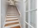Staircase with hardwood steps, white risers, and white trim next to white framed window at 6824 Wood Forest Dr, Cary, NC 27519