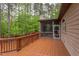 Large stained wood deck leading to a screened porch, surrounded by lush greenery at 7633 Summer Pines Way, Wake Forest, NC 27587