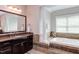 Bright bathroom featuring a soaking tub, neutral tile, and dark vanity with granite countertop at 7633 Summer Pines Way, Wake Forest, NC 27587