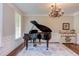 Living room featuring a grand piano, chandelier, and trimwork at 7633 Summer Pines Way, Wake Forest, NC 27587