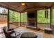 Screened porch with an outdoor fireplace and furniture, overlooks wooded yard at 7633 Summer Pines Way, Wake Forest, NC 27587