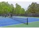 View of the community tennis court with a shaded player area and a backdrop of green trees at 7633 Summer Pines Way, Wake Forest, NC 27587