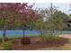 A well-maintained tennis court surrounded by lush landscaping and mature trees, offering a serene playing environment at 7633 Summer Pines Way, Wake Forest, NC 27587