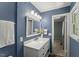 Bathroom vanity with decorative light fixtures, quartz countertop, framed mirror, and painted blue walls at 7653 Summerglen Dr, Raleigh, NC 27615