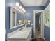 Bathroom vanity with decorative light fixtures, quartz countertop, framed mirror, and painted blue walls at 7653 Summerglen Dr, Raleigh, NC 27615