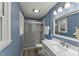 Bathroom features a white vanity, framed mirror, walk-in shower with glass door, and blue painted walls at 7653 Summerglen Dr, Raleigh, NC 27615
