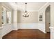 Bright dining area with a classic chandelier, wainscoting, and hardwood flooring at 7728 Cape Charles Dr, Raleigh, NC 27617