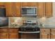 Close-up of the oven and stovetop surrounded by hardwood cabinets and granite countertops at 7728 Cape Charles Dr, Raleigh, NC 27617