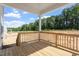 Open back porch with wood flooring and railings overlooking a wooded area with a blue sky above at 90 Cordoba Dr, Franklinton, NC 27525