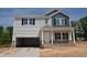 Two-story home with light gray siding, blue accent siding, an open garage and stone accents on the facade at 90 Cordoba Dr, Franklinton, NC 27525