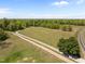 Wide angle aerial view of gravel driveway going through a wide open field at 9400 Wheelers Church E Rd, Hurdle Mills, NC 27541