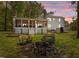Backyard with stone fire pit, covered porch, picnic tables, and seating at dusk, perfect for outdoor entertaining at 9400 Wheelers Church E Rd, Hurdle Mills, NC 27541