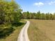 Long gravel driveway winding through a lush, green, wooded property at 9400 Wheelers Church E Rd, Hurdle Mills, NC 27541