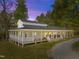 Stunning exterior of a home with a wraparound porch and a metal roof surrounded by mature trees at 9400 Wheelers Church E Rd, Hurdle Mills, NC 27541