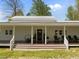 Inviting front porch with rocking chairs, wood flooring, tasteful decor, and a well-manicured lawn at 9400 Wheelers Church E Rd, Hurdle Mills, NC 27541