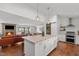 Open-concept kitchen with island, modern appliances, and hardwood floors, flowing into a living room with a stone fireplace at 9400 Wheelers Church E Rd, Hurdle Mills, NC 27541