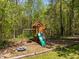Wooden playground with swings, climbing wall, slide, and trampoline, set amidst lush greenery at 9400 Wheelers Church E Rd, Hurdle Mills, NC 27541