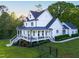 Elegant white farmhouse with a spacious covered porch, rocking chairs, and meticulously maintained landscaping at 1023 Laura Johnson Rd, Pittsboro, NC 27312