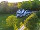 Stunning two-story white home boasts a covered front porch surrounded by lush green lawns and mature trees at 1023 Laura Johnson Rd, Pittsboro, NC 27312