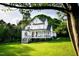 Stunning white farmhouse with a covered porch, rocking chairs, and a well-manicured front lawn at 1023 Laura Johnson Rd, Pittsboro, NC 27312