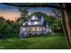 White farmhouse with covered porch and chairs, set against a beautiful sunset and green lawn at 1023 Laura Johnson Rd, Pittsboro, NC 27312