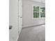 Bedroom with plush carpeting, a large window and a closed door with metal hardware visible in the frame at 103 Loch Ryan Way, Cary, NC 27513