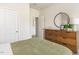 Bedroom featuring a light green bedspread, wooden dresser, and round mirror at 1120 Landen Creek Ln, Zebulon, NC 27597