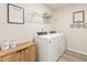 Bright laundry room features a washer, dryer, wire shelf, and wood cabinet at 1120 Landen Creek Ln, Zebulon, NC 27597