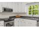 Bright kitchen features white cabinets, stainless steel appliances and sink under a window with a view of the backyard at 1209 Shincliffe Ct, Cary, NC 27511