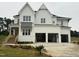 A charming two-story white farmhouse with a three-car garage and manicured front yard at 1217 Azalea Garden Cir, Raleigh, NC 27603