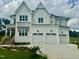 Attractive white home with a multi-car garage, lush landscaping, and a welcoming entrance with wooden accents at 1217 Azalea Garden Cir, Raleigh, NC 27603