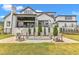 Beautiful backyard with stone patio, fire pit, outdoor seating, and covered deck on a modern white brick home at 1633 Estate Valley Ln, Raleigh, NC 27613