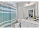 Bright bathroom featuring a shower with a blue striped curtain, white cabinets, and sink at 1633 Estate Valley Ln, Raleigh, NC 27613