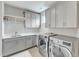 Well-lit laundry room with gray cabinetry, sink, folding counter, and modern washer and dryer at 1633 Estate Valley Ln, Raleigh, NC 27613
