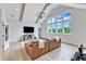 Bright living room with exposed beams, hardwood floors, leather sofa, and large picture windows at 1633 Estate Valley Ln, Raleigh, NC 27613
