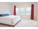 Light-filled bedroom showcasing a bed with a blue lumbar pillow, large windows, and neutral carpeting at 2089 Florine Dr, Apex, NC 27502