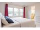 Comfortable bedroom with bed with blue pillow, three windows with red curtains, and an en suite bathroom at 2089 Florine Dr, Apex, NC 27502