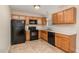 Functional kitchen featuring wooden cabinets, black appliances, and neutral tiled flooring at 2112 Ballston Pl, Knightdale, NC 27545
