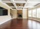 Spacious living room featuring hardwood floors, stone fireplace, coffered ceilings, and natural light at 212 Listening Ridge Ln, Cary, NC 27519