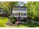 Two-story house with a light yellow exterior, black shutters, brick foundation and lush landscaping at 213 Beechtree Dr, Cary, NC 27513